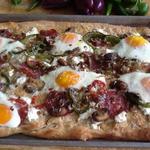 Breakfast pizza with eggs and fresh greens